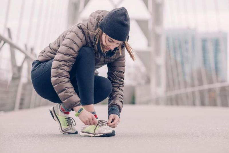 "Woman jogger with healthy feet is tying laces FootBrews"